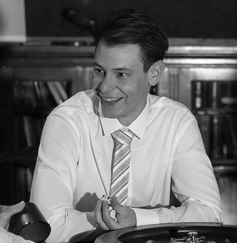 Jakub Szypicyn, smiling, in a white shirt and striped tie